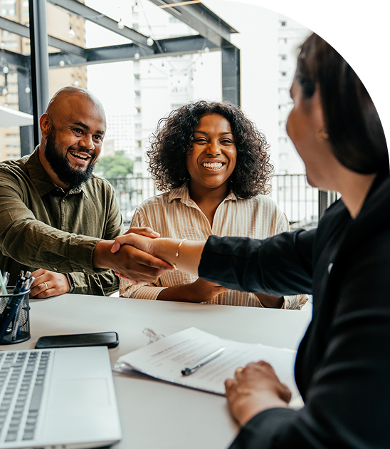 Two people shaking hands with a third person in a business meeting.